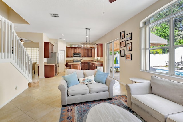 living room with light tile patterned flooring, ceiling fan with notable chandelier, and sink