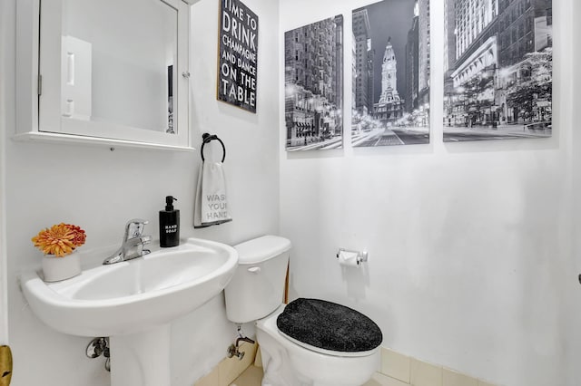 bathroom featuring toilet, sink, and tile patterned flooring