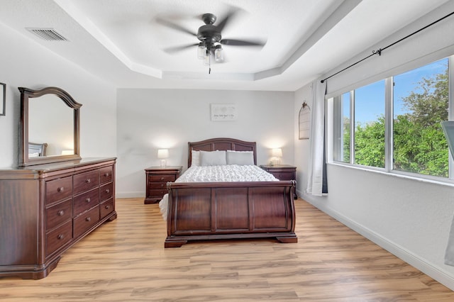 bedroom featuring a raised ceiling, light hardwood / wood-style flooring, and ceiling fan