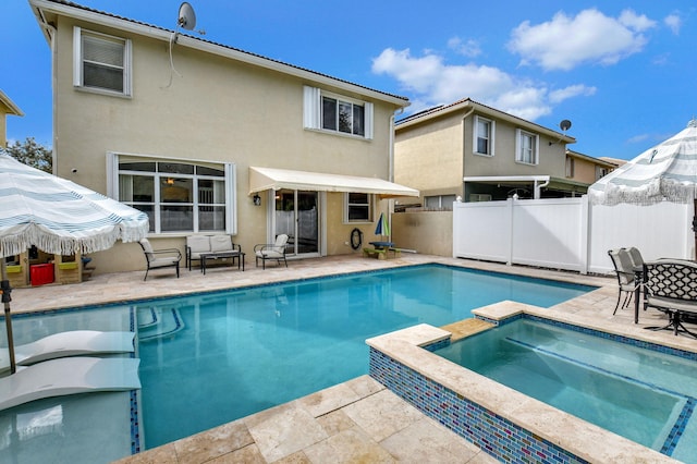 rear view of house with a swimming pool with hot tub and a patio