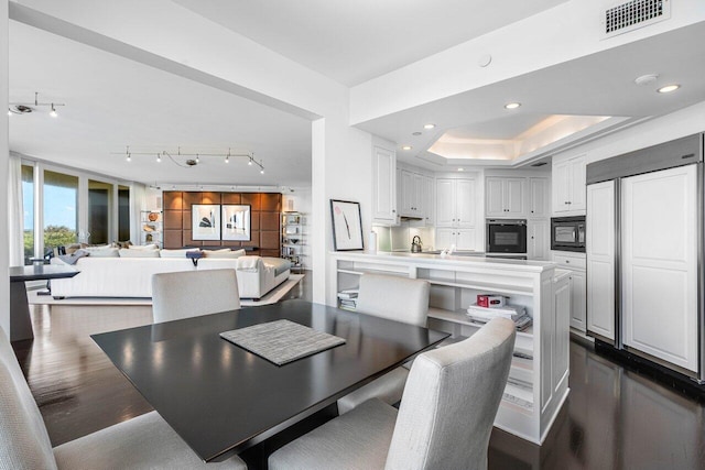 dining area featuring a raised ceiling and dark hardwood / wood-style flooring