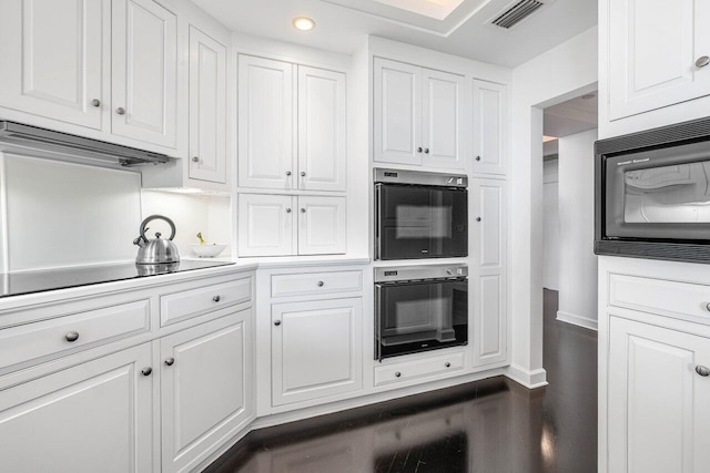 kitchen featuring dark hardwood / wood-style flooring, white cabinetry, and black appliances