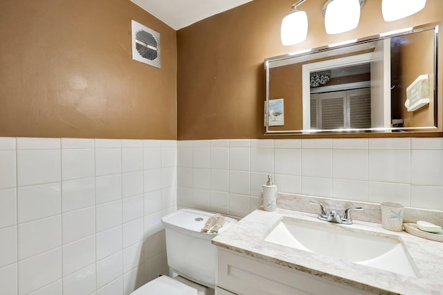 bathroom featuring vanity, toilet, and tile walls