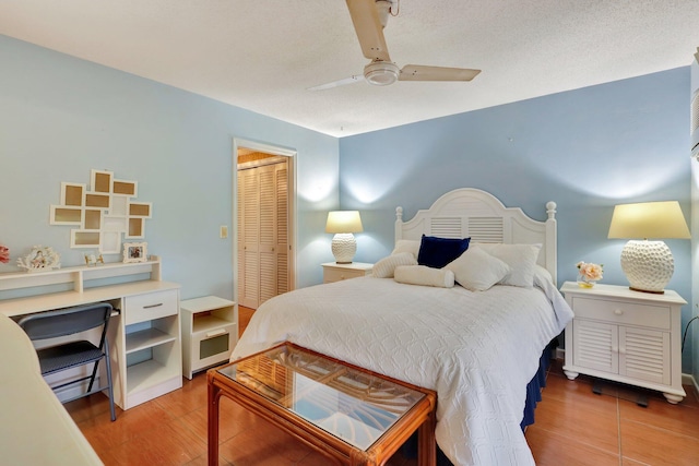 bedroom featuring a closet, wood-type flooring, ceiling fan, and a textured ceiling