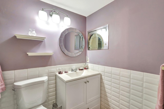 bathroom featuring vanity, toilet, and tile walls