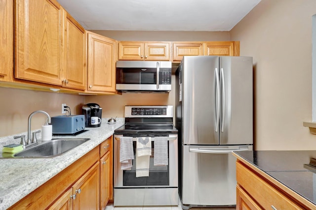 kitchen with light stone counters, light tile patterned flooring, appliances with stainless steel finishes, light brown cabinetry, and sink