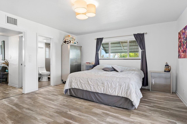 bedroom with hardwood / wood-style floors and ensuite bathroom