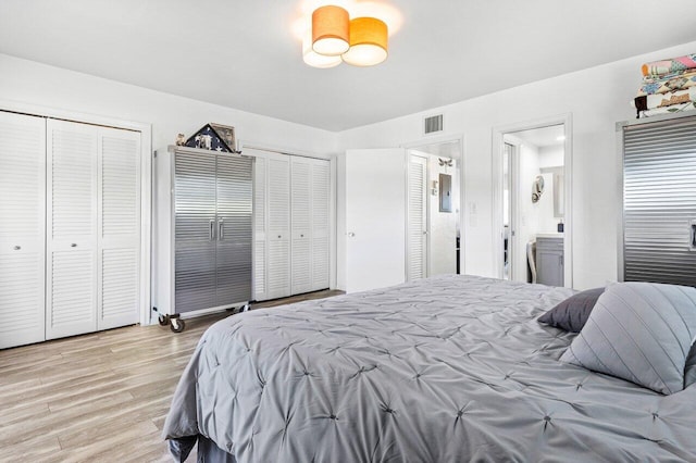 bedroom with light wood-type flooring, connected bathroom, and multiple closets