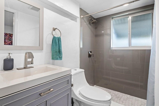 bathroom featuring vanity, toilet, and tiled shower