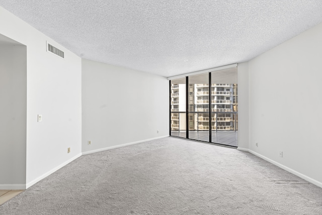 carpeted empty room featuring a textured ceiling