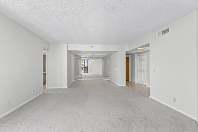 unfurnished room featuring light colored carpet and a textured ceiling