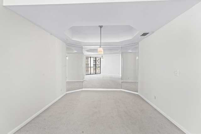 empty room featuring light colored carpet and a tray ceiling