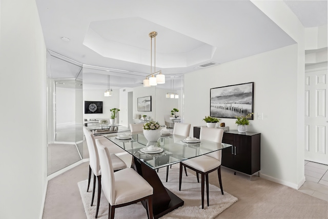 dining space with light carpet and a tray ceiling