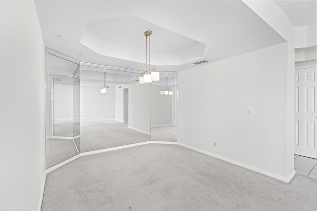 spare room with a tray ceiling and carpet