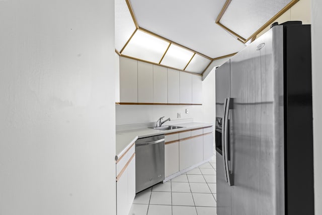 kitchen featuring stainless steel appliances, sink, light tile patterned floors, white cabinets, and lofted ceiling