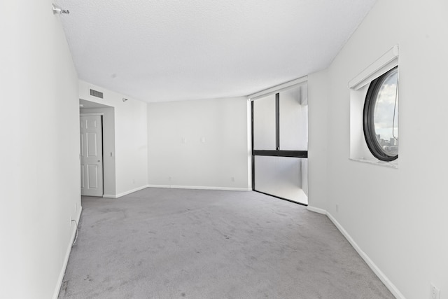 unfurnished room with light colored carpet and a textured ceiling