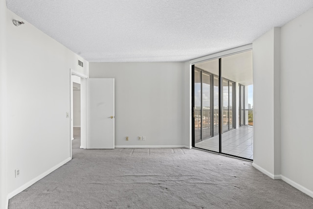 carpeted empty room with a textured ceiling