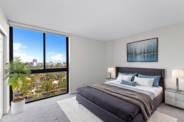 bedroom with light carpet, a wall of windows, and multiple windows