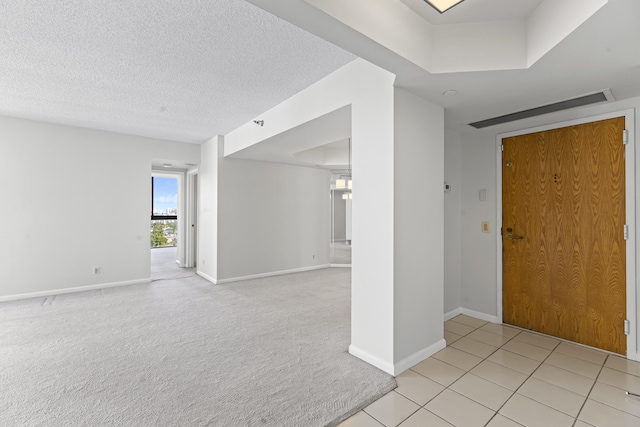 foyer with light carpet and a textured ceiling