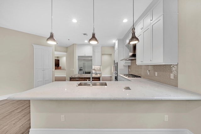 kitchen with kitchen peninsula, stainless steel appliances, sink, pendant lighting, and white cabinetry