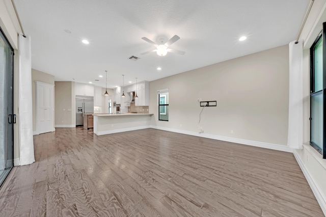 unfurnished living room featuring ceiling fan and light hardwood / wood-style floors