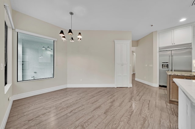 unfurnished dining area with light hardwood / wood-style floors and a notable chandelier