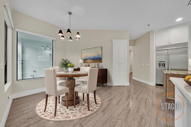 dining area with a chandelier, light hardwood / wood-style flooring, and lofted ceiling