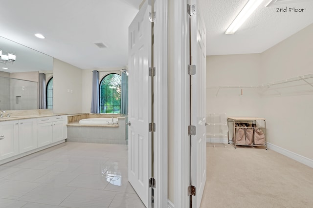 bathroom featuring tile patterned flooring, a textured ceiling, vanity, and separate shower and tub