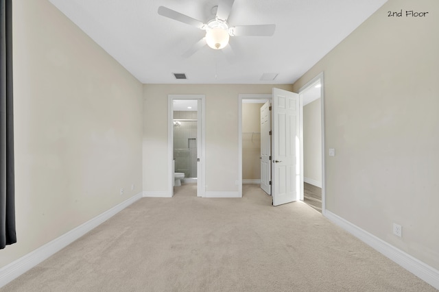 unfurnished bedroom with light carpet, ensuite bath, ceiling fan, a spacious closet, and a closet