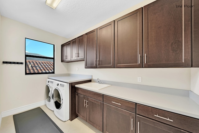 washroom with cabinets, sink, washing machine and dryer, light tile patterned floors, and a textured ceiling