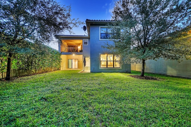 rear view of property with a lawn and a balcony