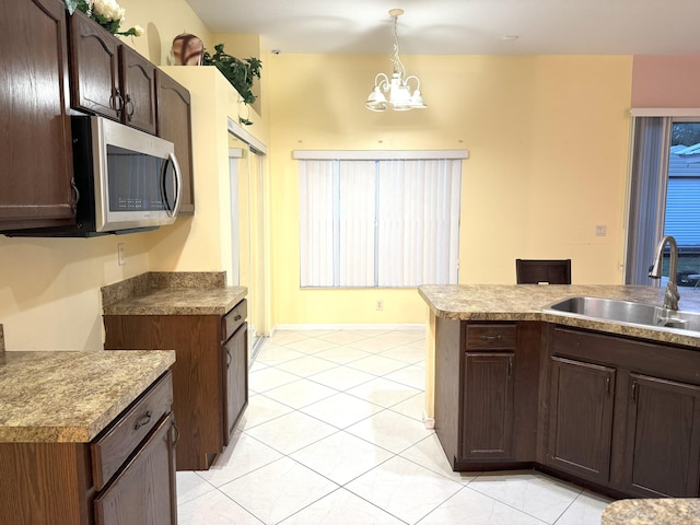 kitchen with dark brown cabinetry, sink, a chandelier, decorative light fixtures, and light tile patterned floors