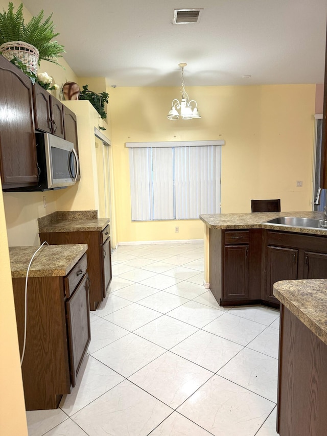 kitchen with sink, dark brown cabinets, pendant lighting, and an inviting chandelier