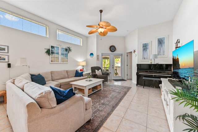 living room featuring ceiling fan, light tile patterned flooring, a towering ceiling, and french doors