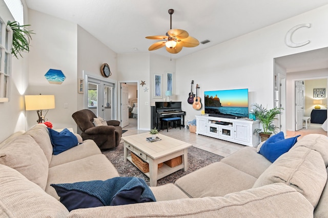 living room with a towering ceiling, ceiling fan, french doors, and light tile patterned floors