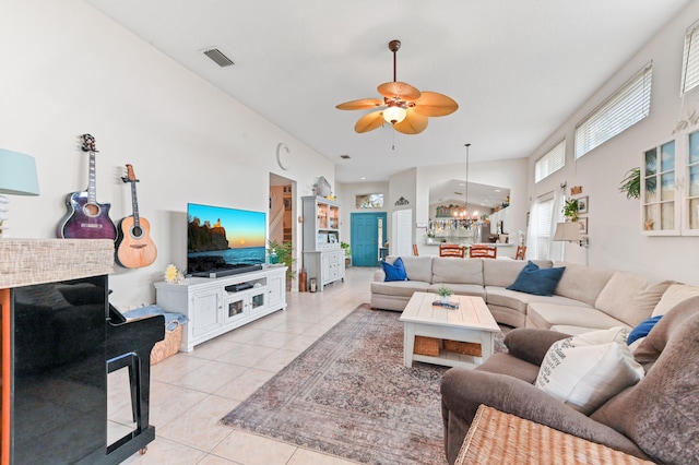 tiled living room featuring ceiling fan with notable chandelier and high vaulted ceiling