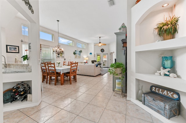 dining area featuring a high ceiling, ceiling fan with notable chandelier, and light tile patterned flooring