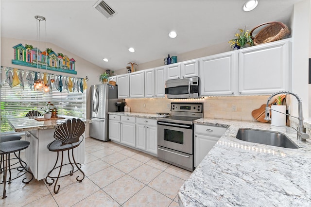 kitchen featuring appliances with stainless steel finishes, sink, pendant lighting, white cabinetry, and lofted ceiling