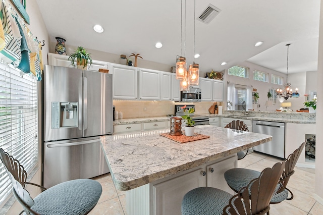 kitchen featuring a wealth of natural light, a kitchen island, decorative light fixtures, and appliances with stainless steel finishes