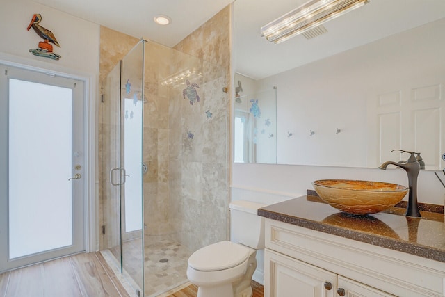 bathroom featuring vanity, toilet, wood-type flooring, and a shower with door