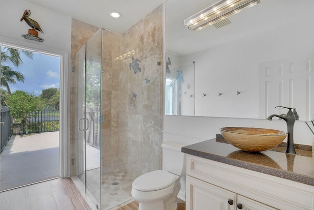 bathroom with hardwood / wood-style floors, vanity, toilet, and an enclosed shower