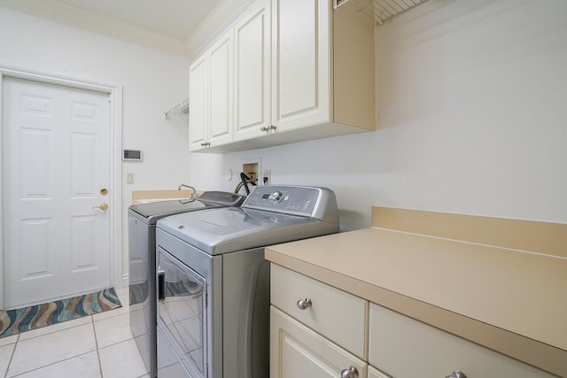 laundry area featuring washing machine and clothes dryer, crown molding, light tile patterned floors, and cabinets