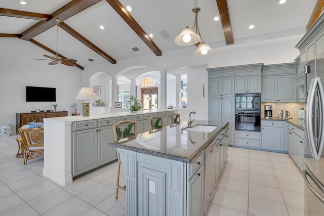 kitchen featuring black appliances, sink, lofted ceiling with beams, a center island with sink, and gray cabinets