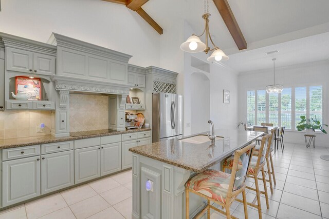 kitchen with beam ceiling, sink, stainless steel refrigerator, and an inviting chandelier