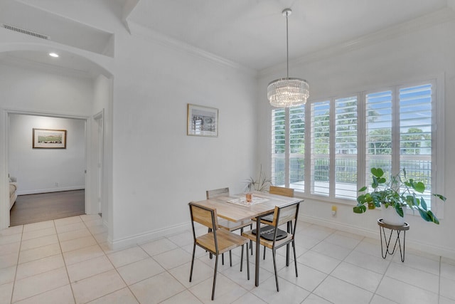 dining area featuring crown molding, light tile patterned floors, and an inviting chandelier