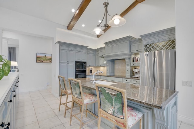 kitchen featuring sink, beamed ceiling, a breakfast bar area, a kitchen island with sink, and black appliances