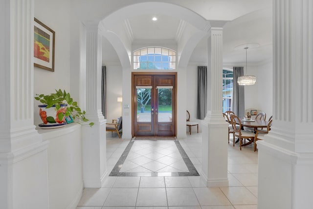 entryway featuring ornate columns, light tile patterned flooring, ornamental molding, and an inviting chandelier