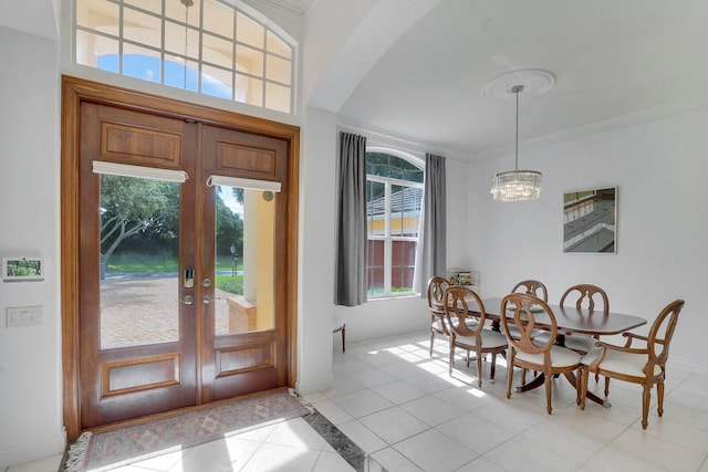 foyer with light tile patterned floors, french doors, ornamental molding, and a notable chandelier