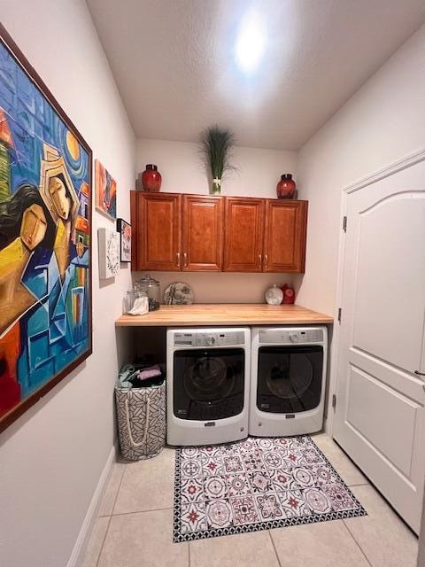 laundry area featuring cabinets, separate washer and dryer, and light tile patterned floors