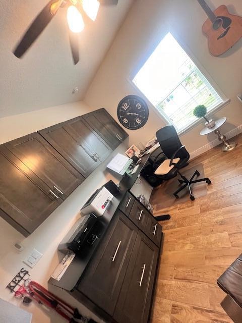 kitchen featuring ceiling fan, lofted ceiling, dark brown cabinetry, and light hardwood / wood-style floors